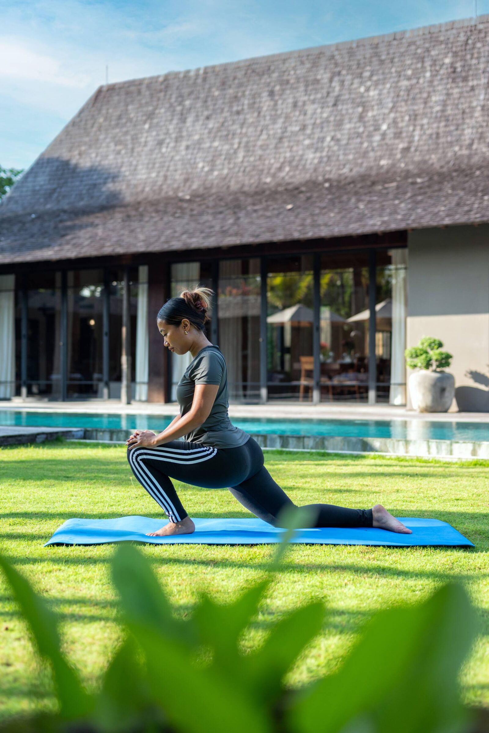 A guest practising yoga on the lawn beside the pool in the morning
