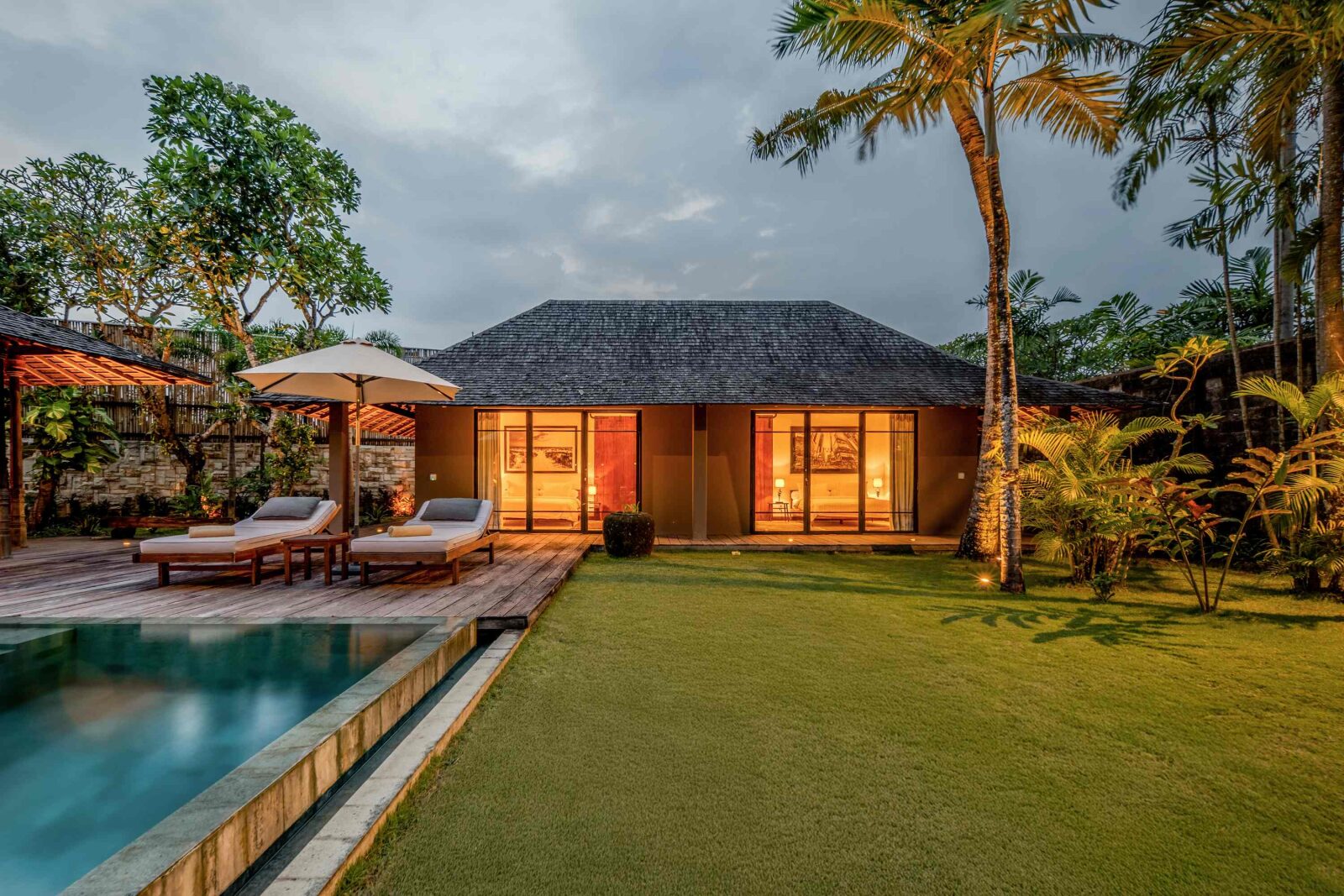 The pool, lawn and villa at dusk