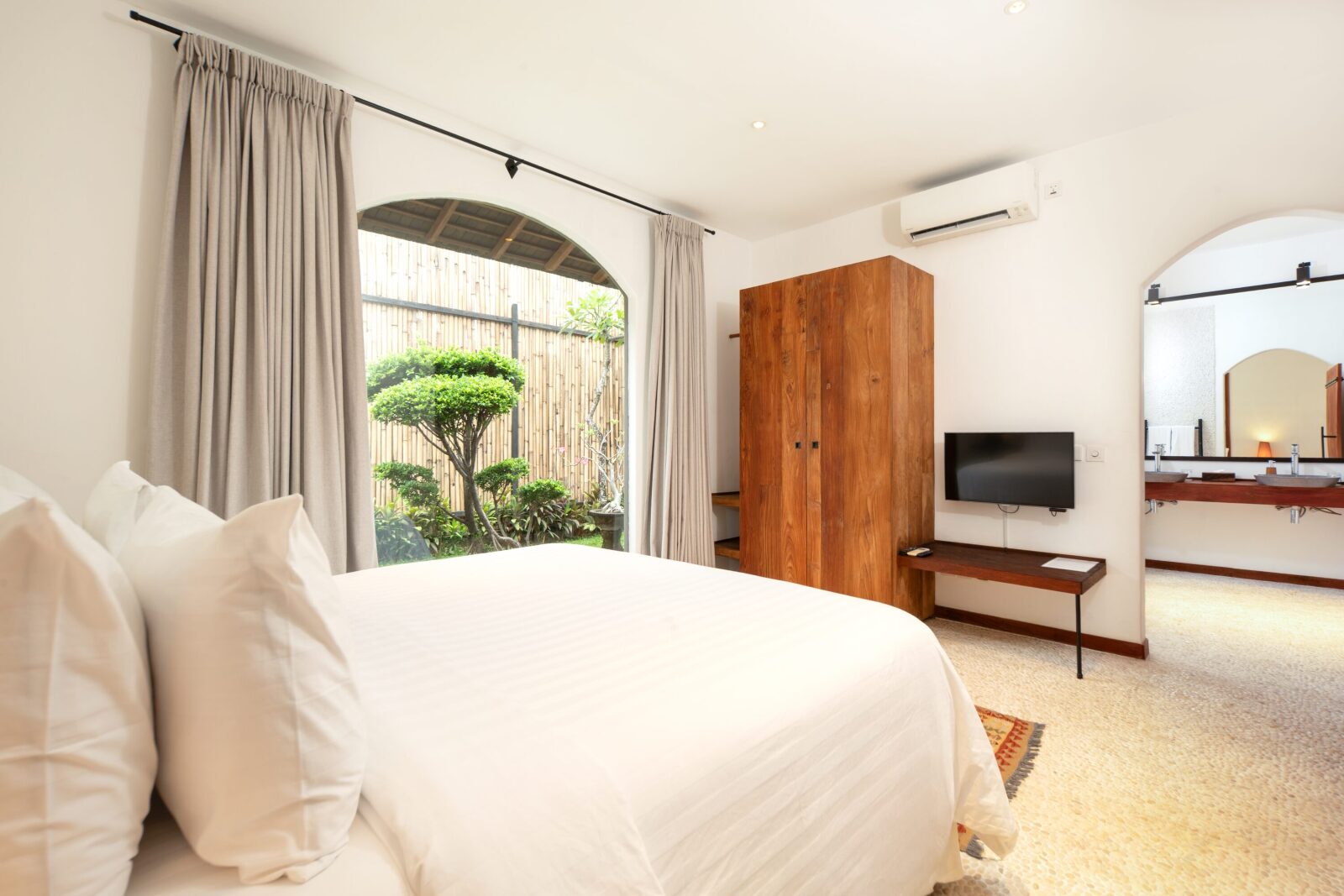The garden-view bedroom's bed and teak wardrobe