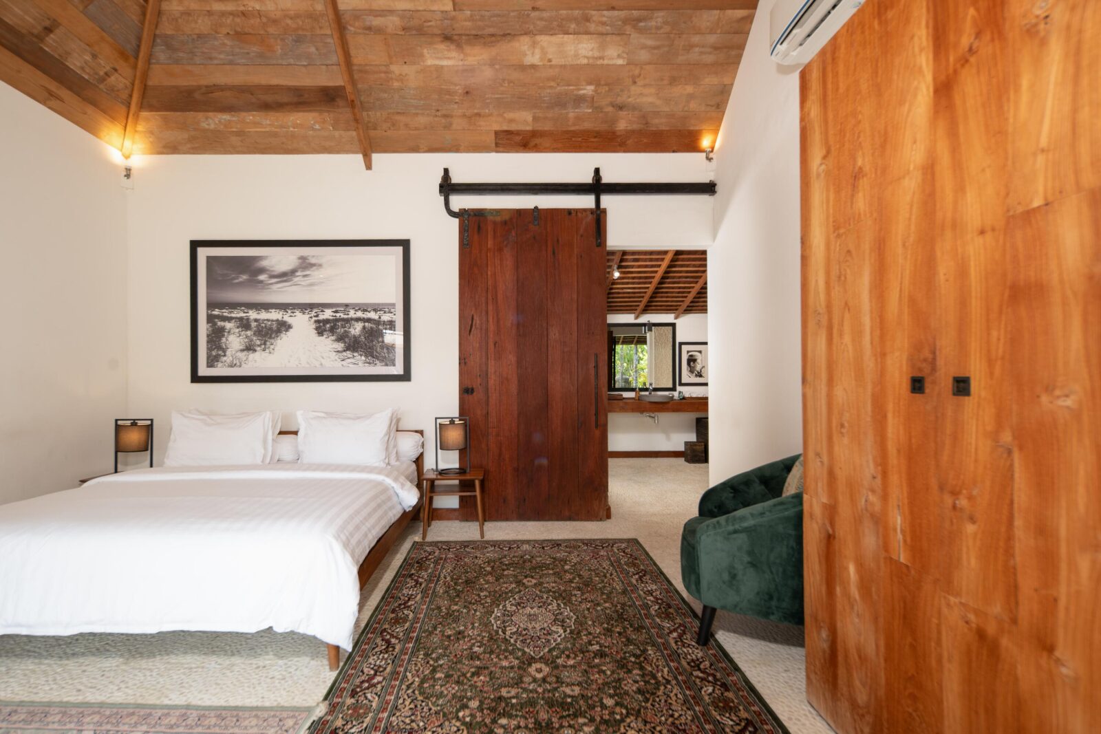 A pool house bedroom with its sliding teak barn door