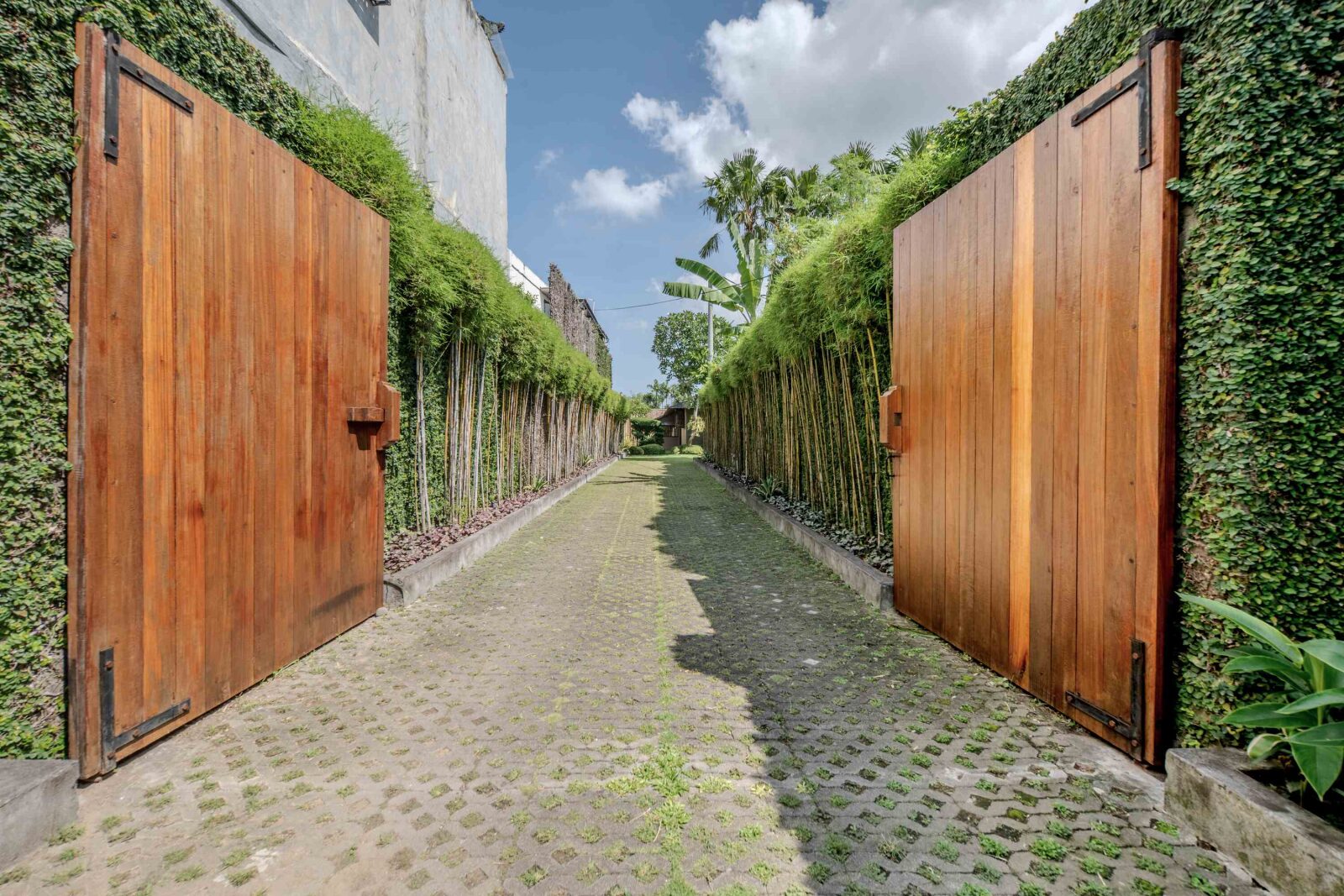 The teak gates standing open onto the private driveway